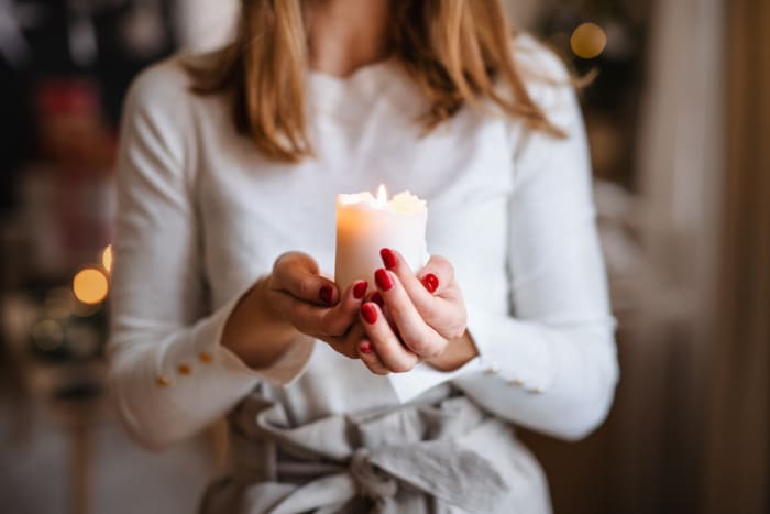 unrecognizable-young-woman-indoors-at-home-at-christmas-holding-candle