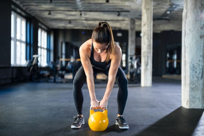 young-woman-lifting-kettlebell-in-gym